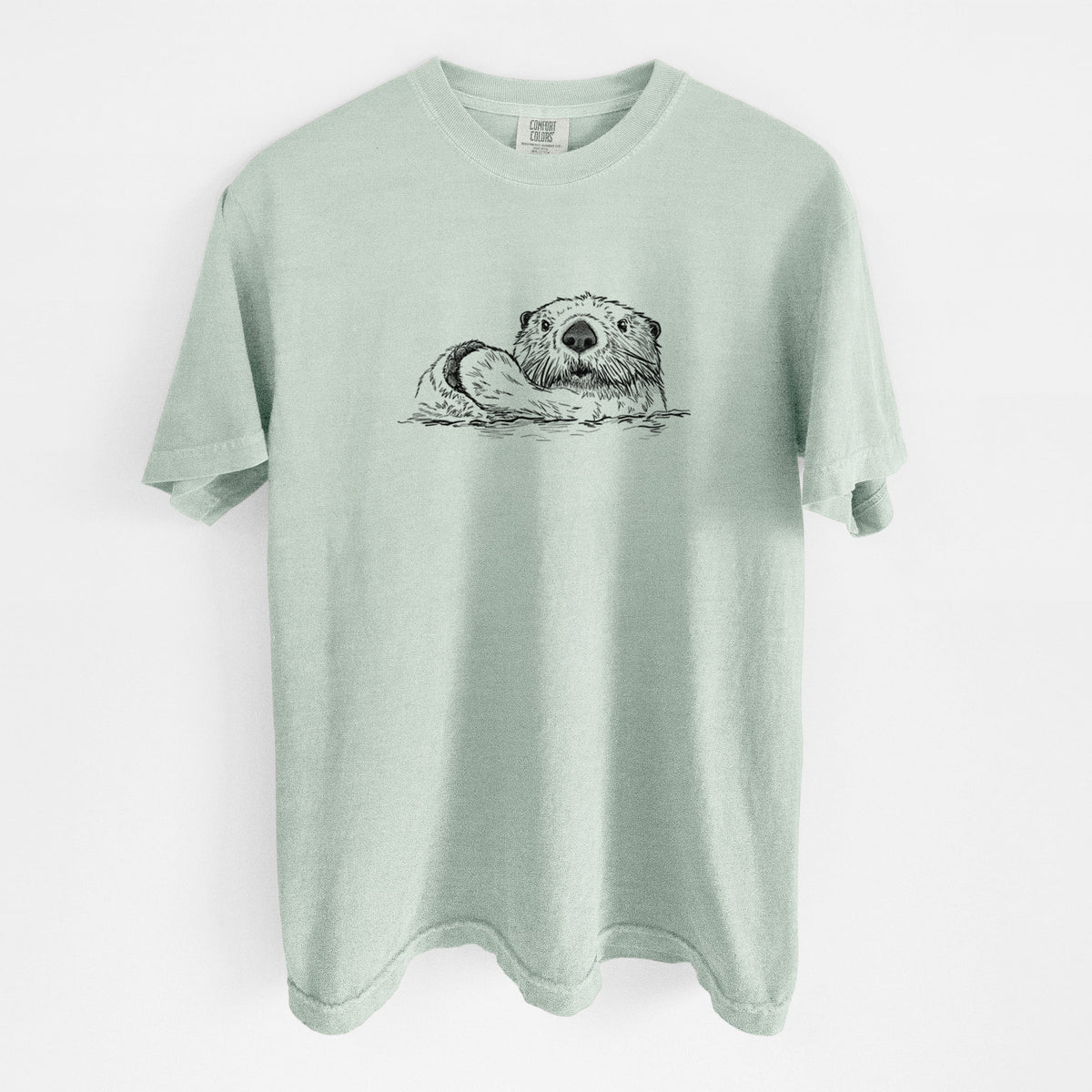 Bay green Comfort Colors t-shirt laid flat, printed with a black ink illustration of a northern river otter peeking out of the water.