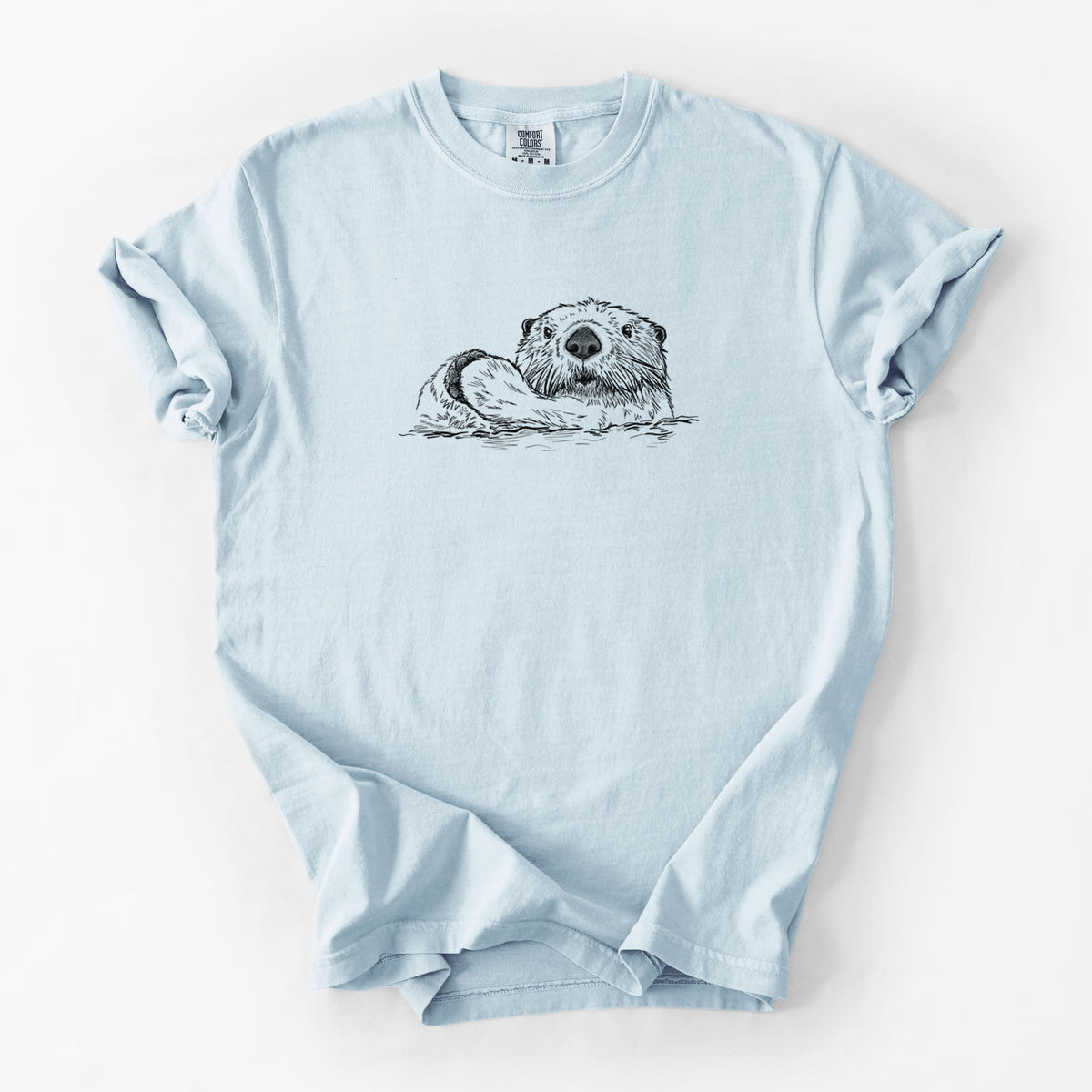 Chambray blue Comfort Colors t-shirt laid flat, printed with a black ink illustration of a northern river otter peeking out of the water.