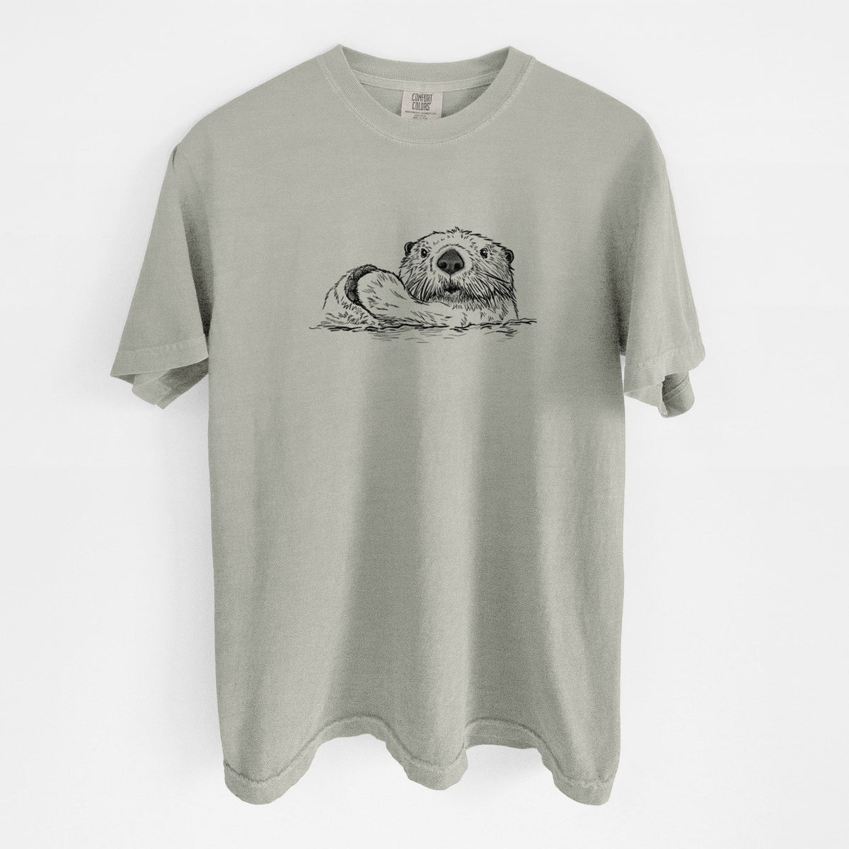 Sandstone beige Comfort Colors t-shirt laid flat, printed with a black ink illustration of a northern river otter peeking out of the water.