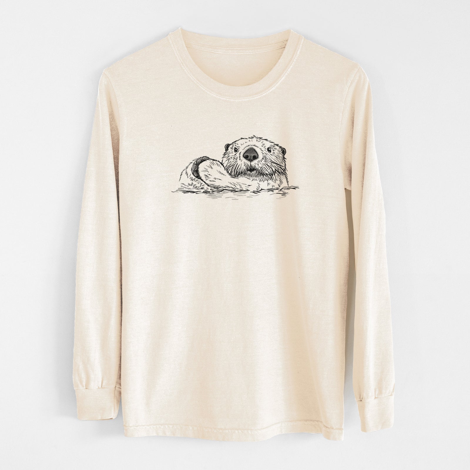 Ivory Comfort Colors long sleeve shirt laid flat, printed with a black ink illustration of a northern river otter peeking out of the water.