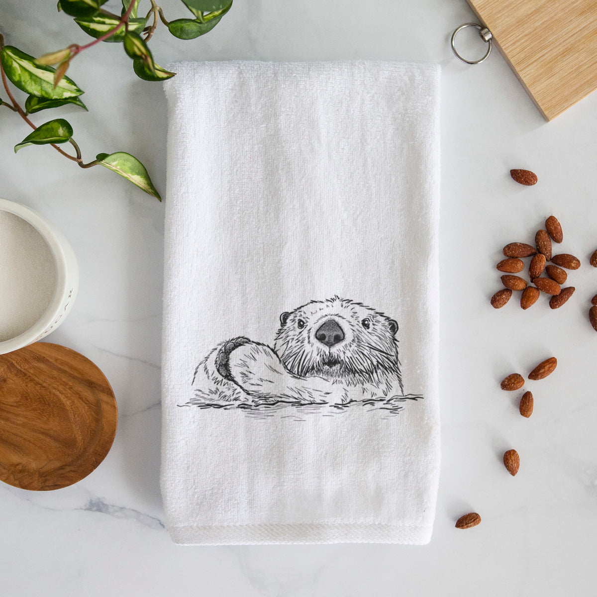 White hand towel printed with a black ink illustration of a northern river otter peeking out of the water.