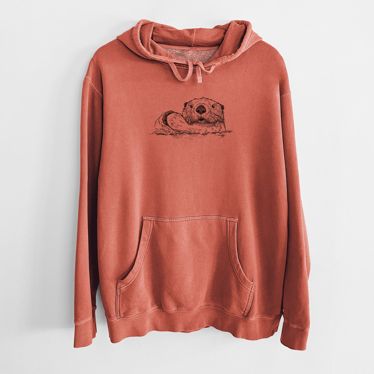 Amber orange pigment dyed hoodie laid flat, printed with a black ink illustration of a northern river otter peeking out of the water.