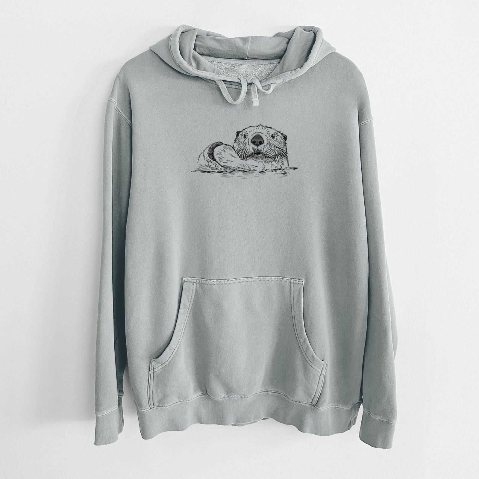 Sage green pigment dyed hoodie laid flat, printed with a black ink illustration of a northern river otter peeking out of the water.