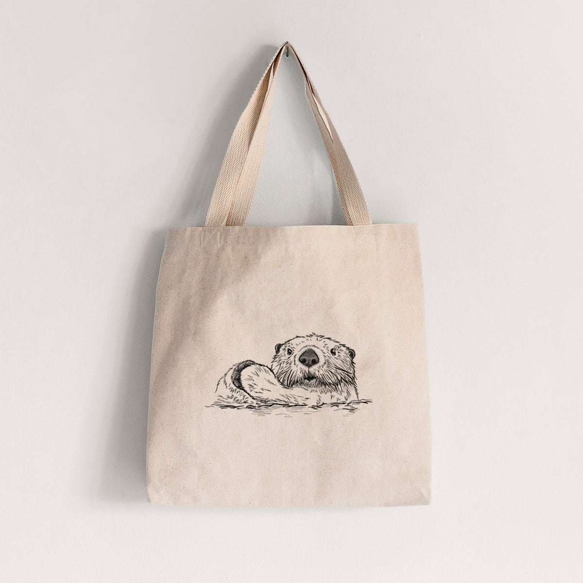 Natural canvas tote bag printed with a black ink illustration of a northern river otter peeking out of the water.