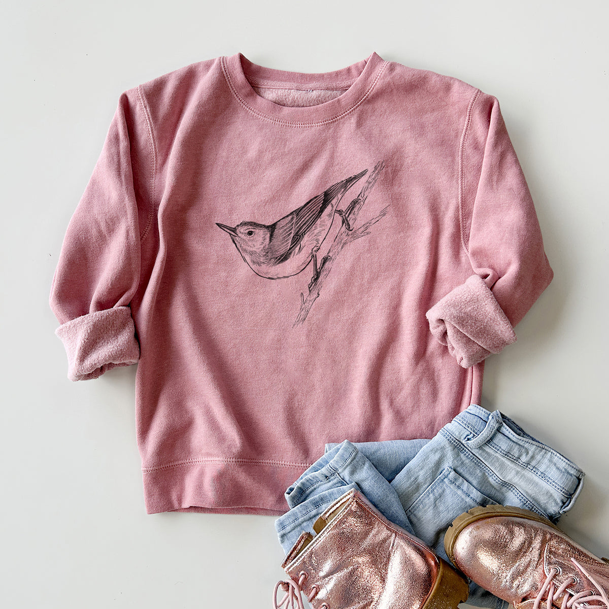 Youth crewneck sweatshirt printed with a detailed black ink sketch of a nuthatch clinging to a branch, styled flat with jeans and boots.