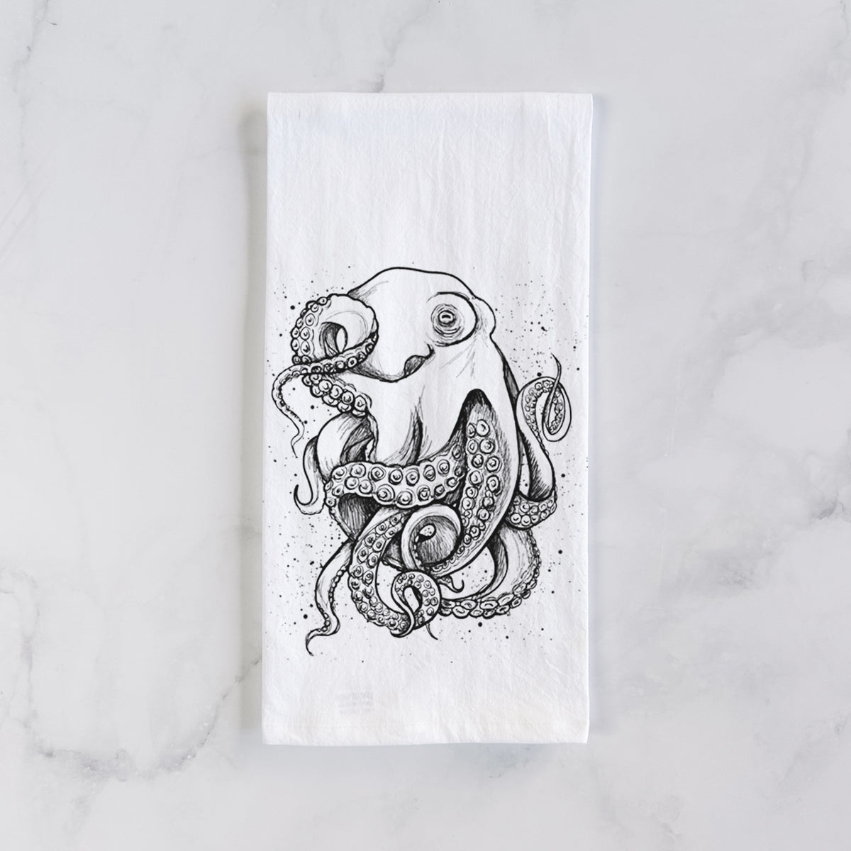 White cotton tea towel laid flat on marble, printed with a detailed black ink illustration of a common octopus with curling tentacles.