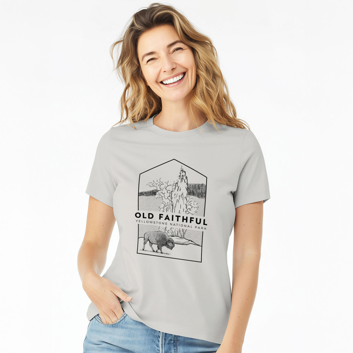 Woman wearing a lunar grey women's relaxed fit cotton t-shirt printed with a black line art badge of the Old Faithful geyser erupting with a bison nearby, with the words Old Faithful, Yellowstone National Park.