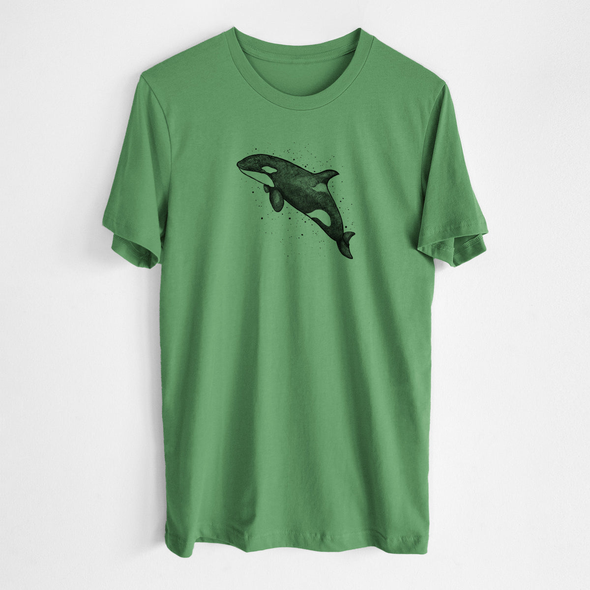 Leaf green lightweight cotton t-shirt laid flat, printed with a black ink illustration of an orca leaping, with ink splatters.