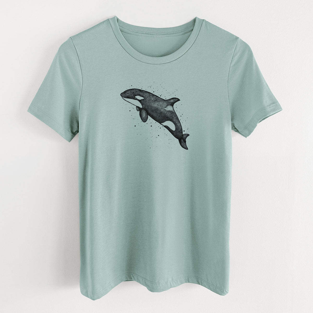 Dusty blue women's relaxed fit cotton t-shirt laid flat, printed with a black ink illustration of an orca leaping, with ink splatters.