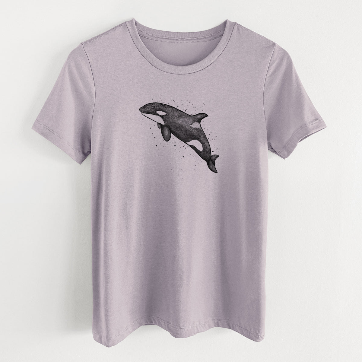 Light violet women's relaxed fit cotton t-shirt laid flat, printed with a black ink illustration of an orca leaping, with ink splatters.