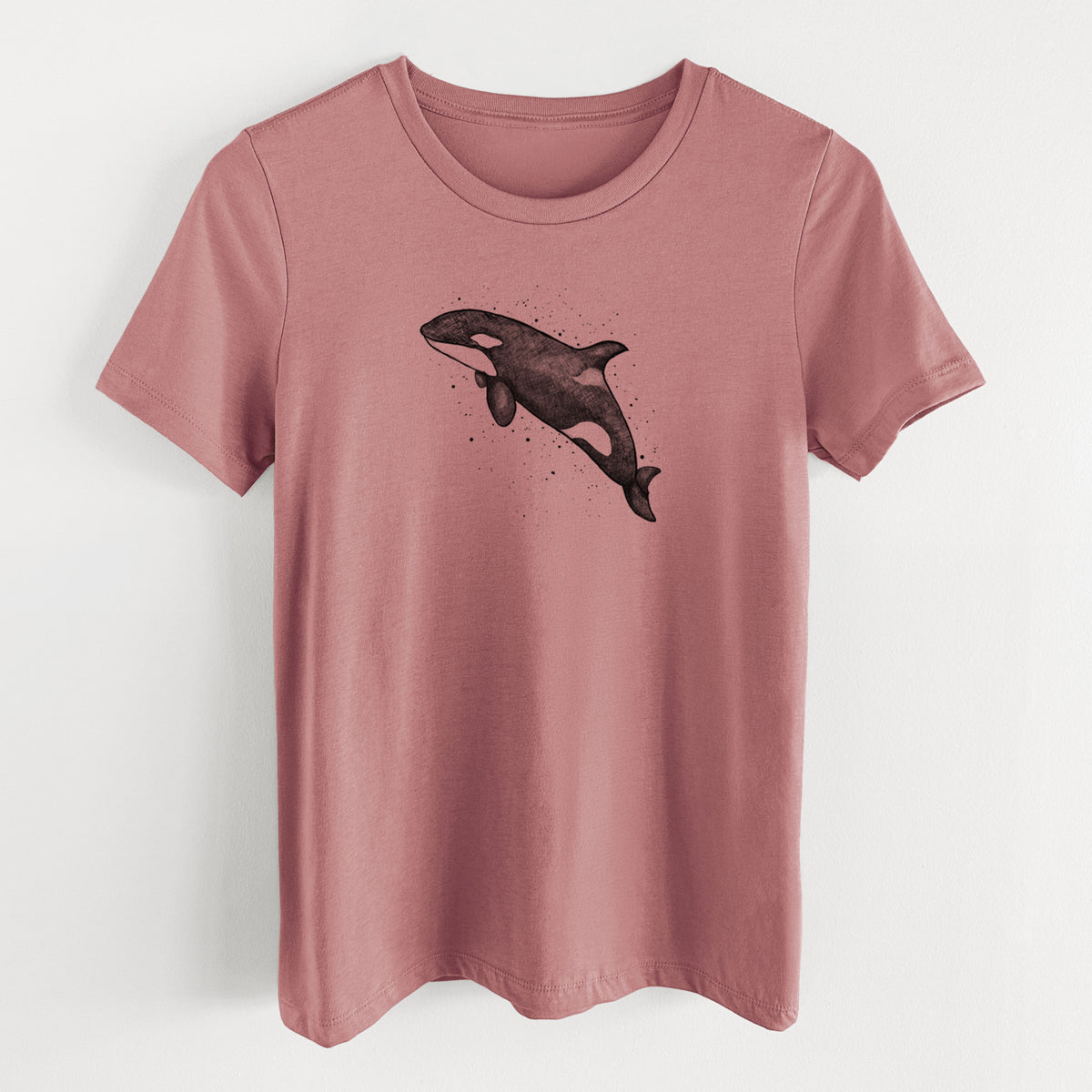 Mauve pink women's relaxed fit cotton t-shirt laid flat, printed with a black ink illustration of an orca leaping, with ink splatters.