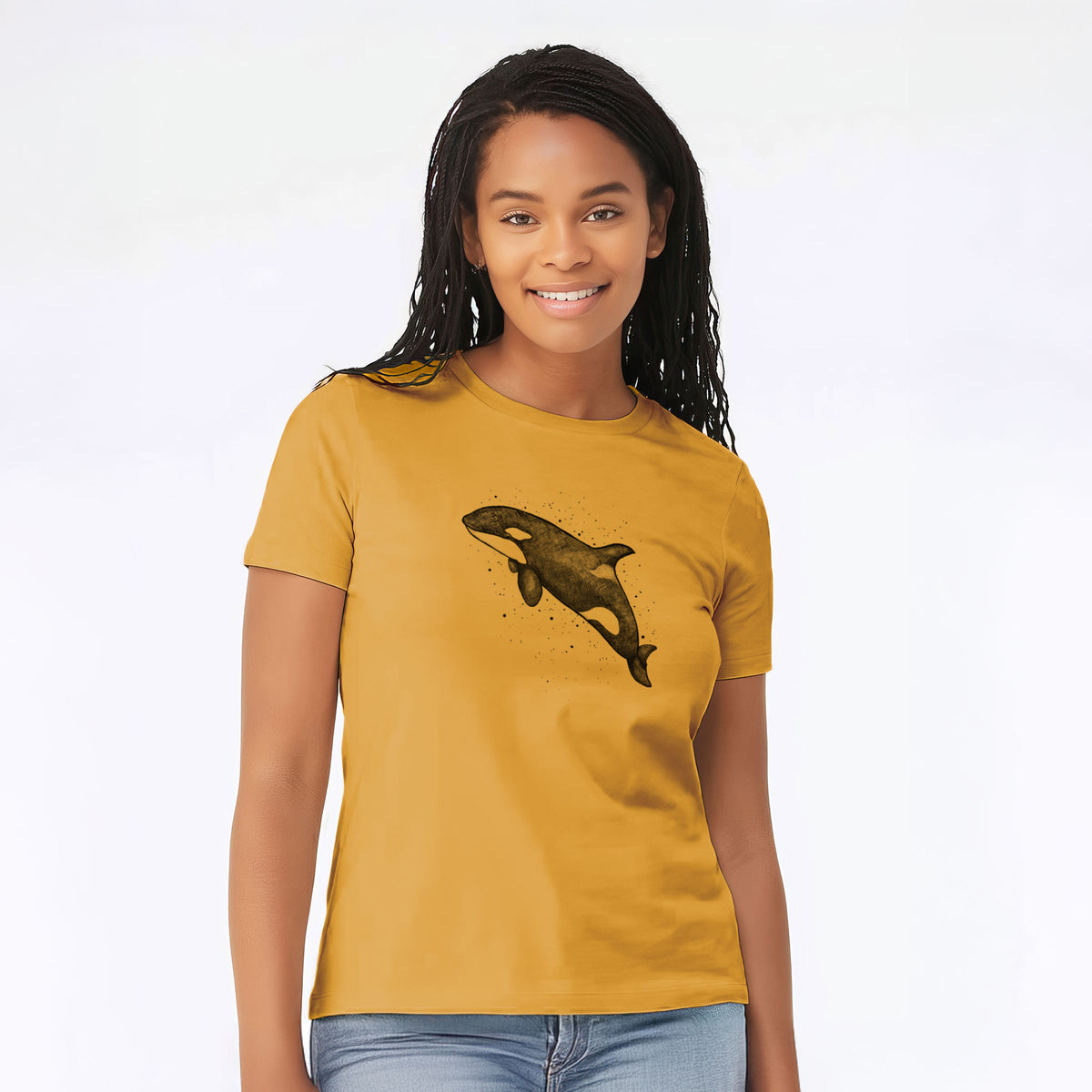 Woman wearing a mustard yellow women's relaxed fit cotton t-shirt printed with a black ink illustration of an orca leaping, with ink splatters.