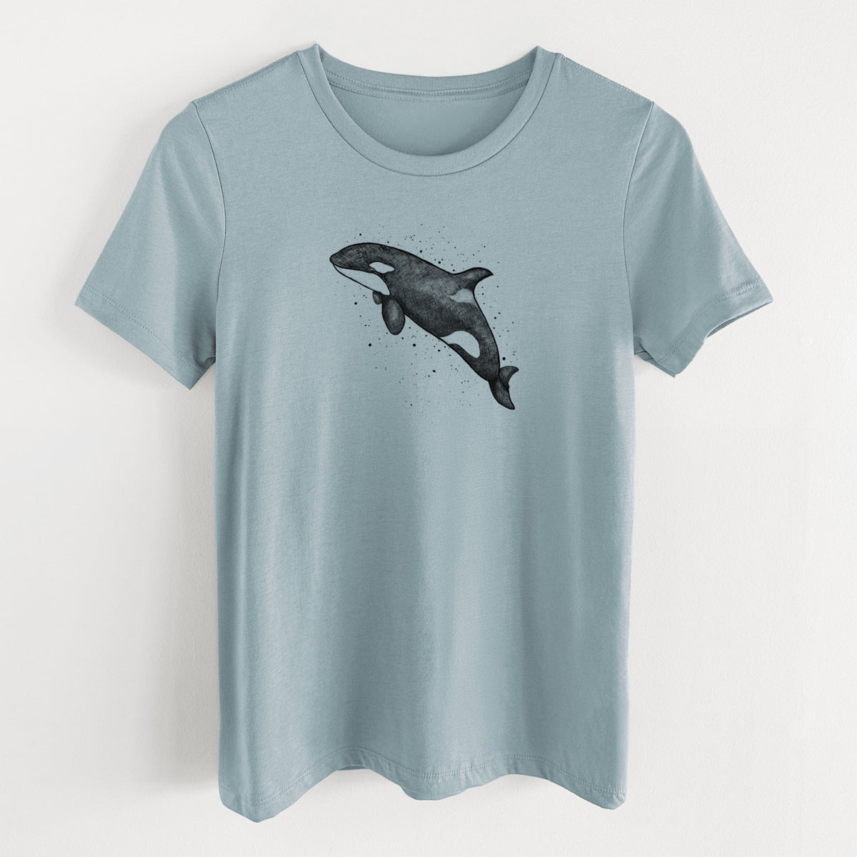 Vintage denim women's relaxed fit cotton t-shirt laid flat, printed with a black ink illustration of an orca leaping, with ink splatters.