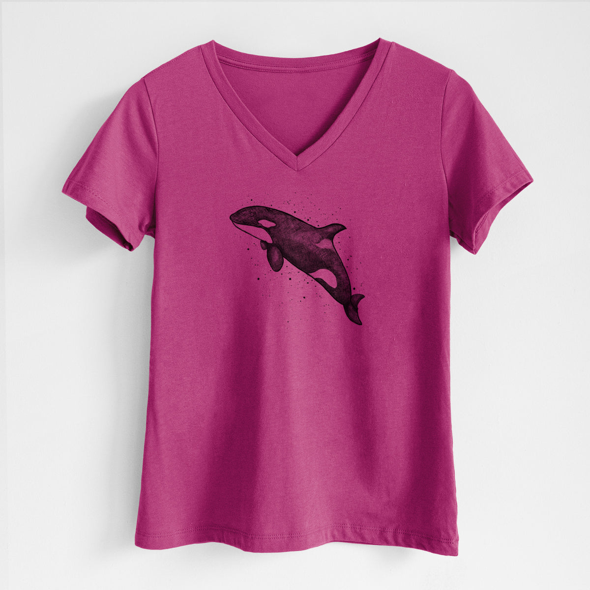 Berry pink women's relaxed fit cotton V-neck t-shirt laid flat, printed with a black ink illustration of an orca leaping, with ink splatters.