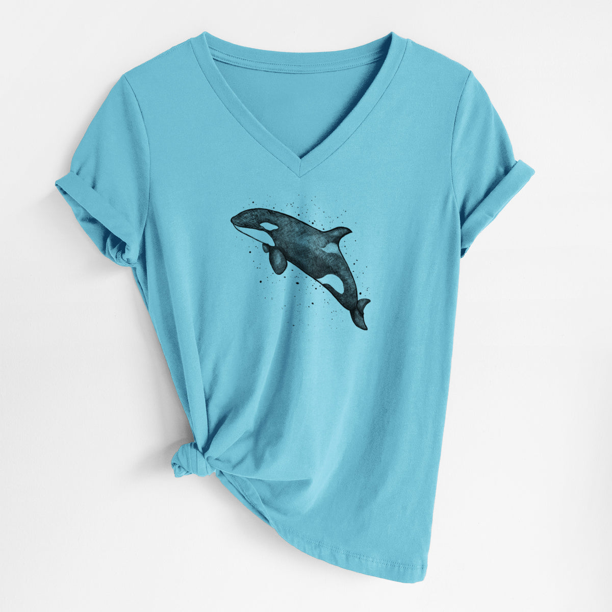 Turquoise women's relaxed fit cotton V-neck t-shirt laid flat, printed with a black ink illustration of an orca leaping, with ink splatters.