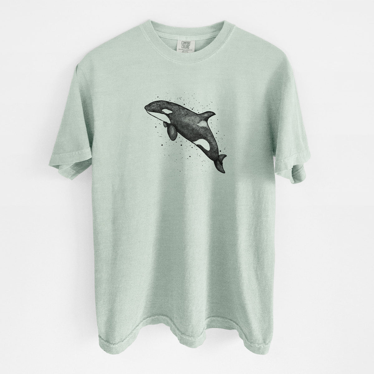 Bay green Comfort Colors t-shirt laid flat, printed with a black ink illustration of an orca leaping, with ink splatters.