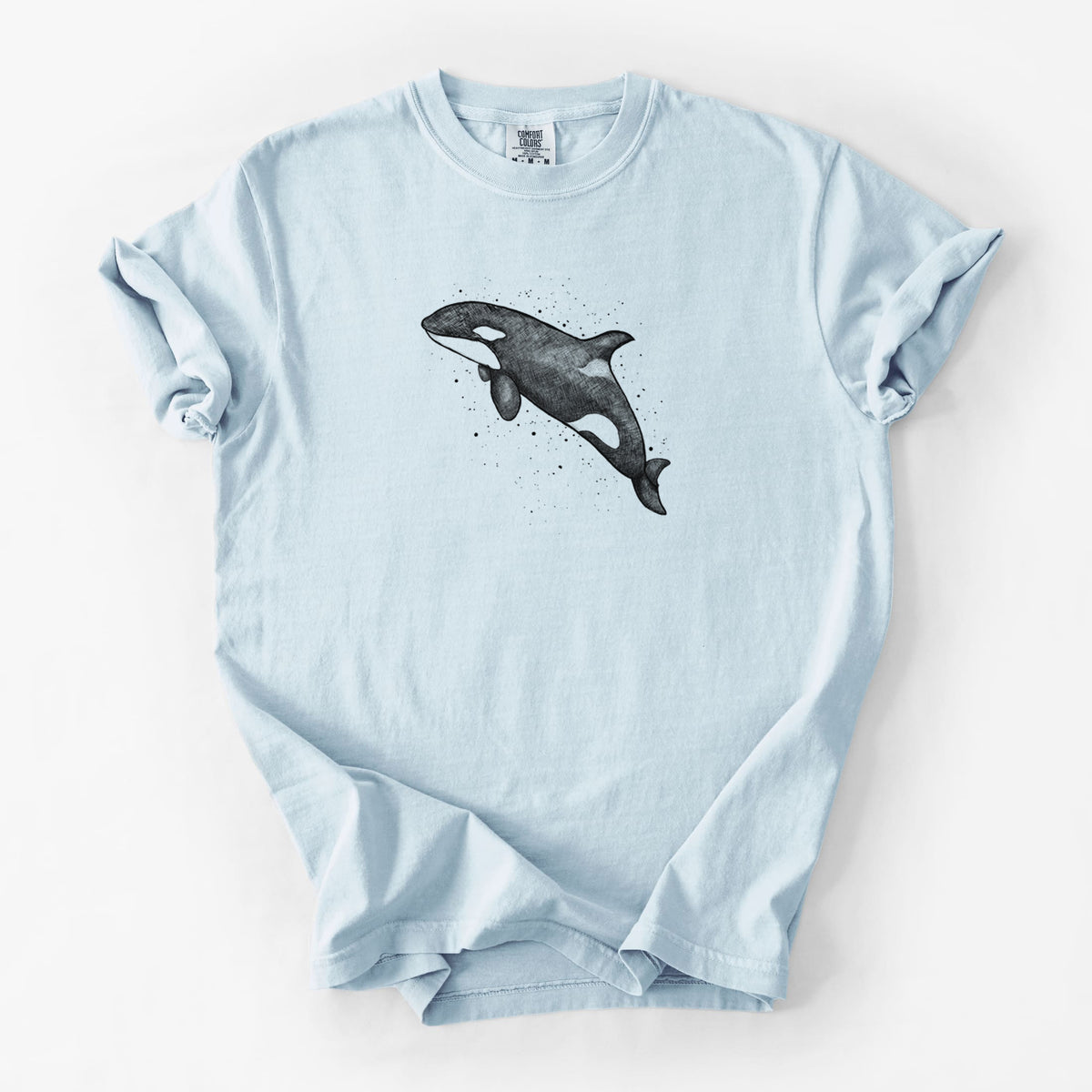 Chambray blue Comfort Colors t-shirt laid flat, printed with a black ink illustration of an orca leaping, with ink splatters.