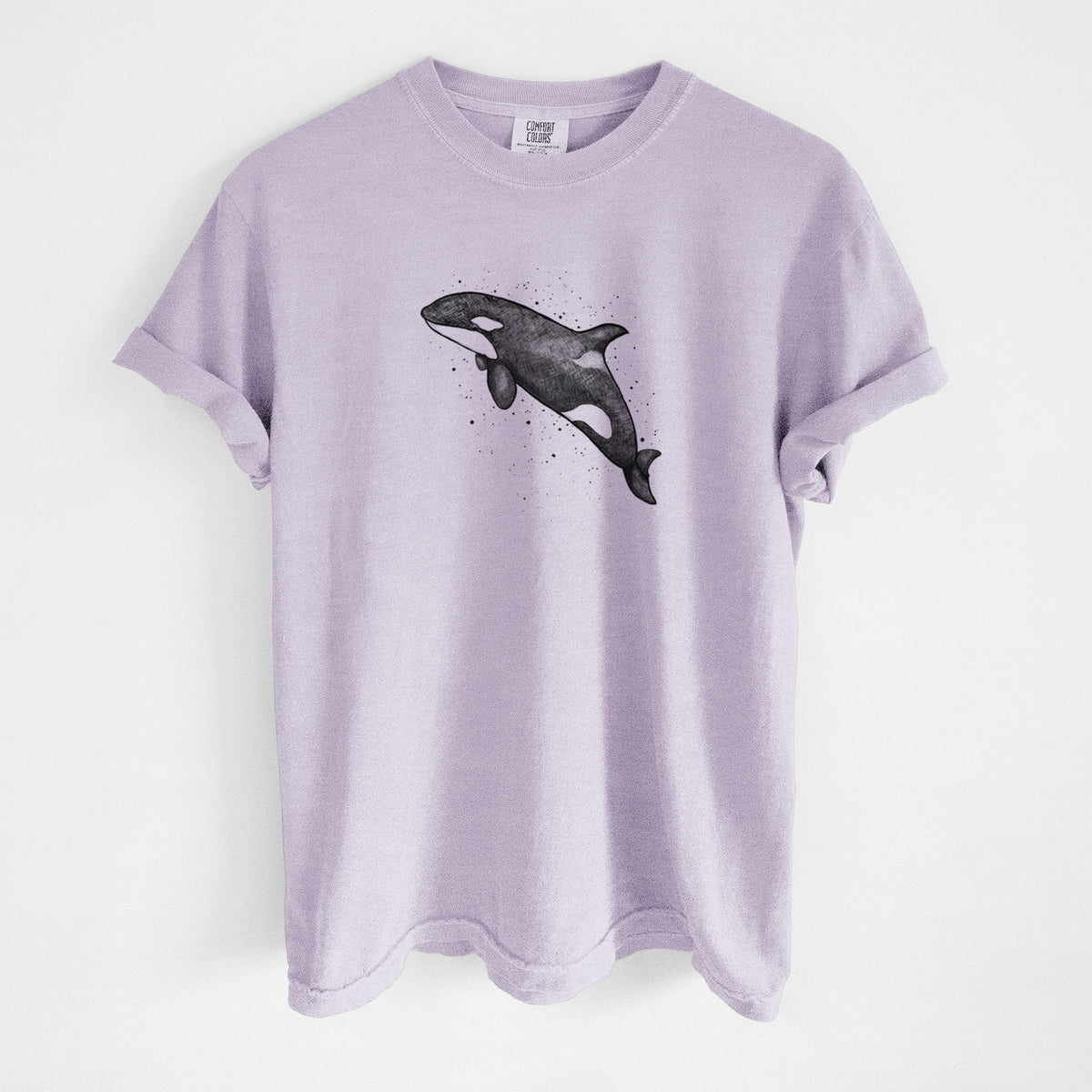 Orchid purple Comfort Colors t-shirt laid flat, printed with a black ink illustration of an orca leaping, with ink splatters.
