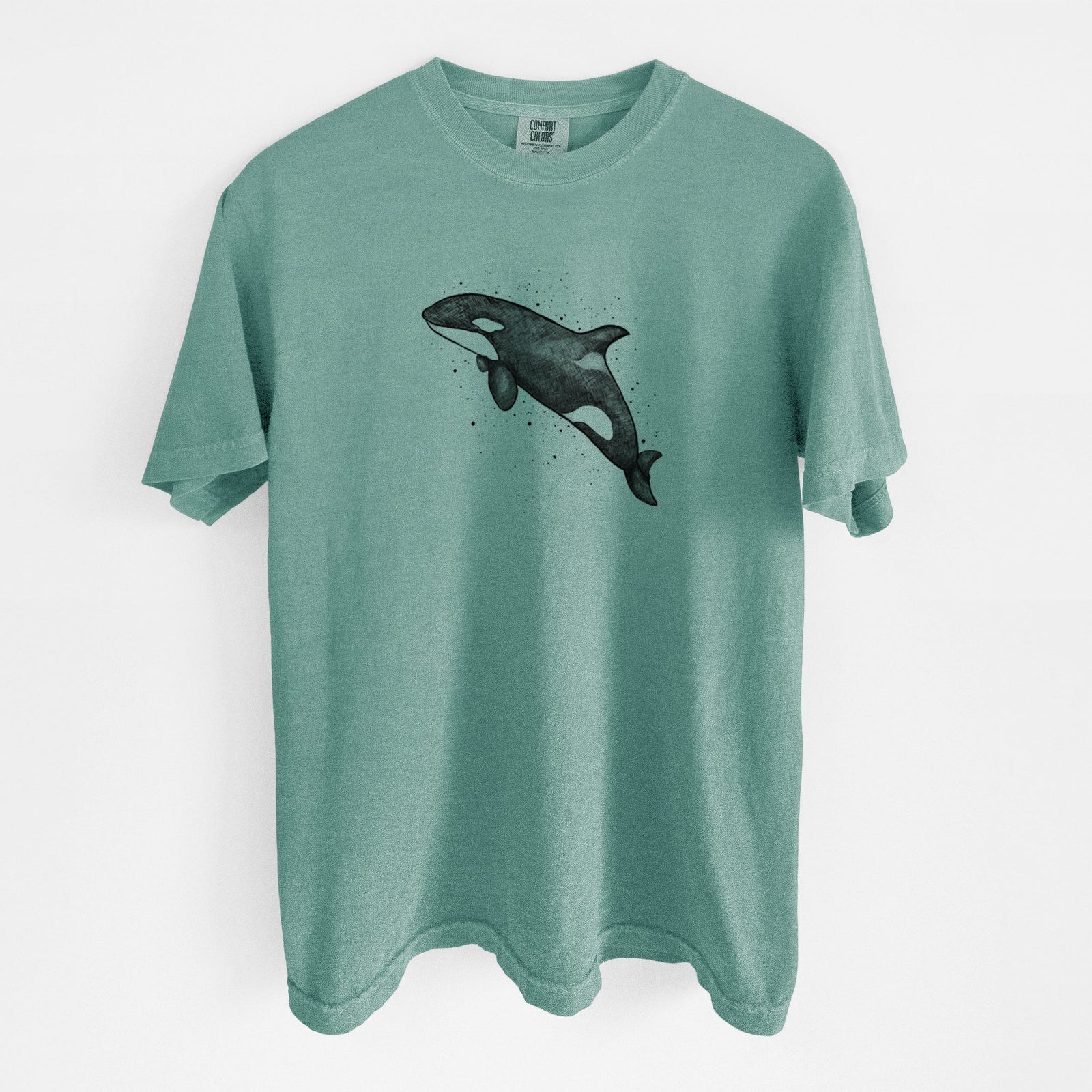 Blue jean Comfort Colors t-shirt laid flat, printed with a black ink illustration of an orca leaping, with ink splatters.