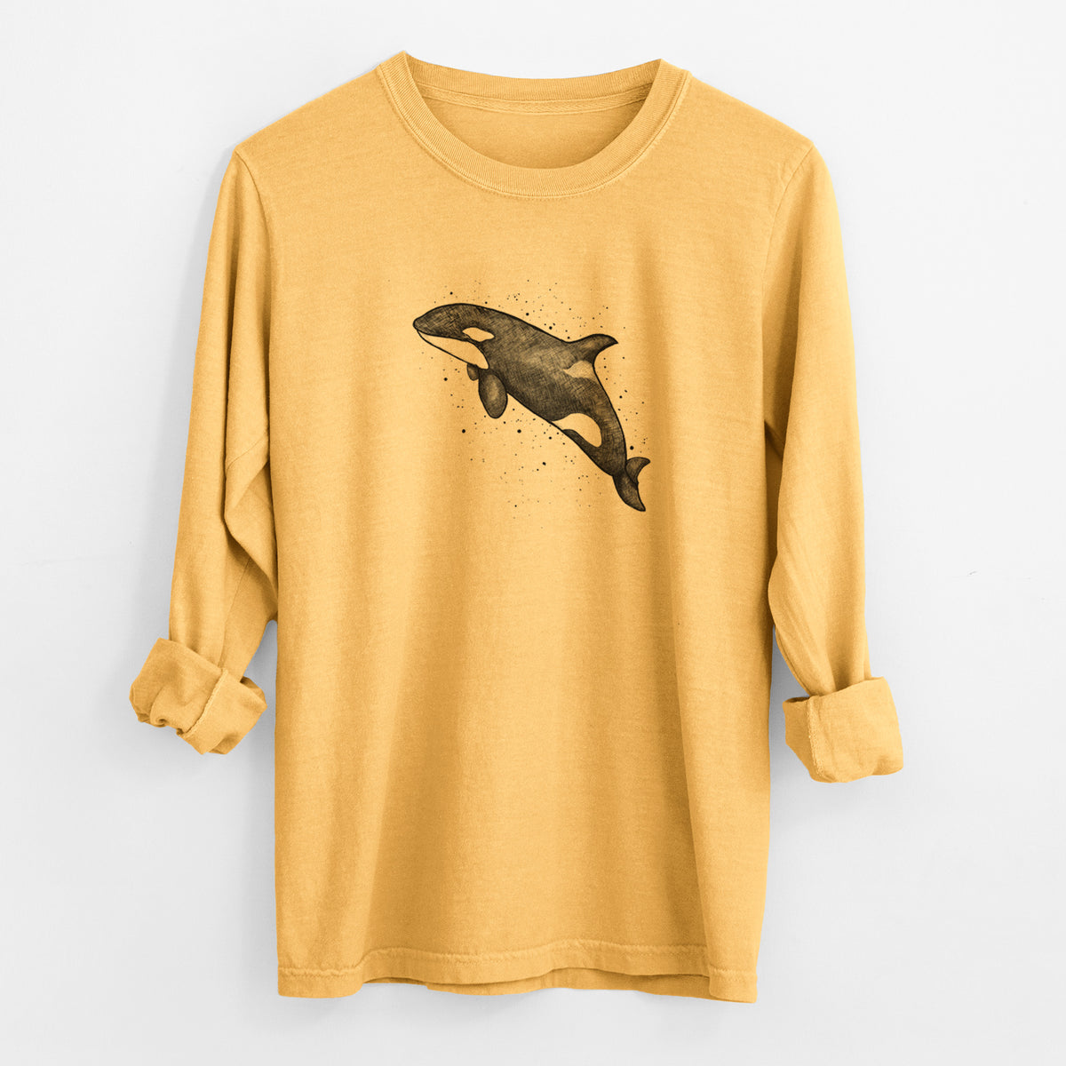 Golden wheat yellow Comfort Colors long sleeve shirt laid flat with the cuffs rolled, printed with a black ink illustration of an orca leaping, with ink splatters.