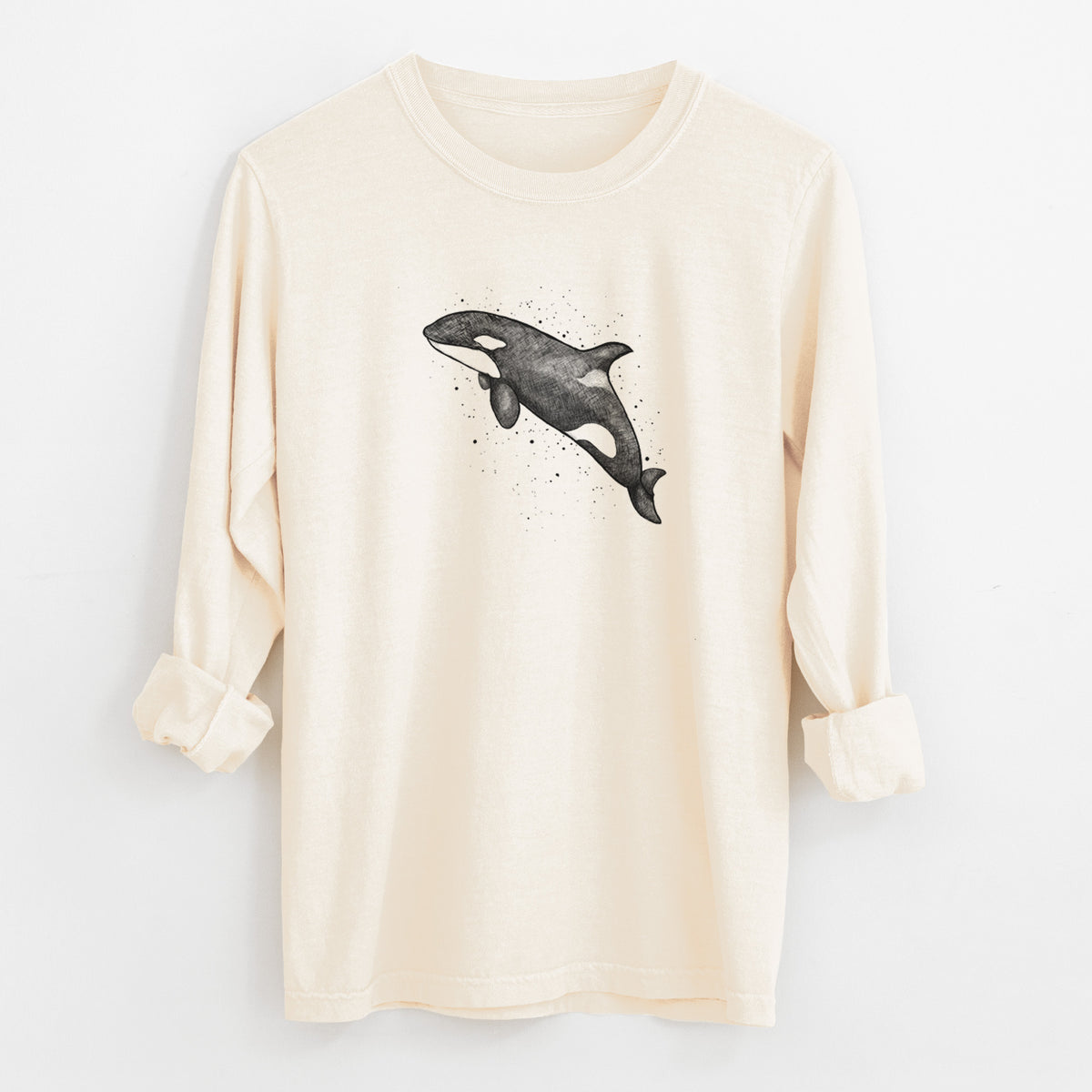 Ivory Comfort Colors long sleeve shirt laid flat with the cuffs rolled, printed with a black ink illustration of an orca leaping, with ink splatters.