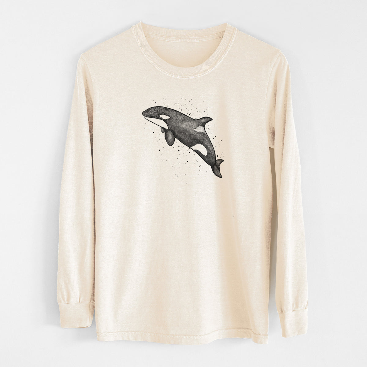 Ivory Comfort Colors long sleeve shirt laid flat, printed with a black ink illustration of an orca leaping, with ink splatters.