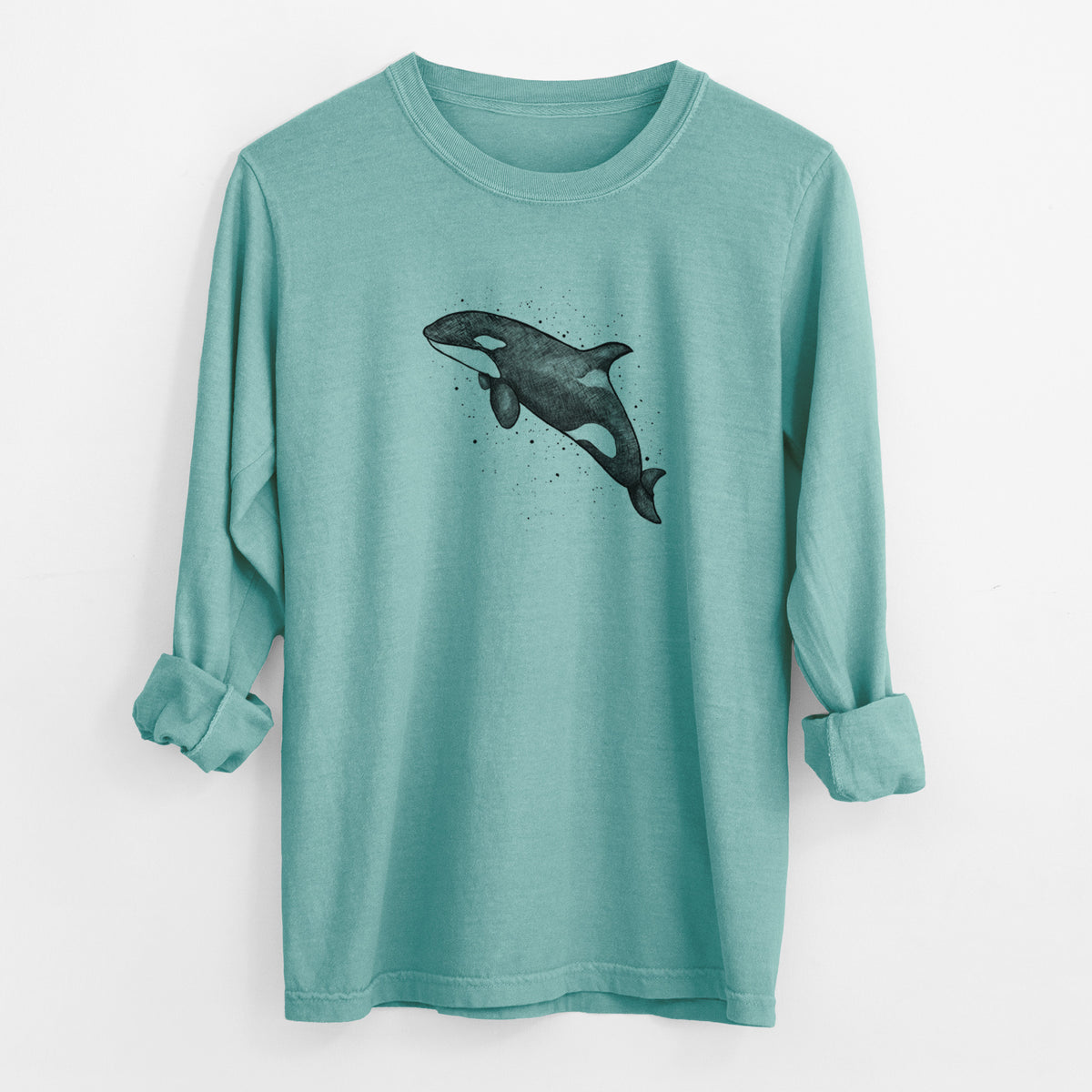 Reef green Comfort Colors long sleeve shirt laid flat with the cuffs rolled, printed with a black ink illustration of an orca leaping, with ink splatters.