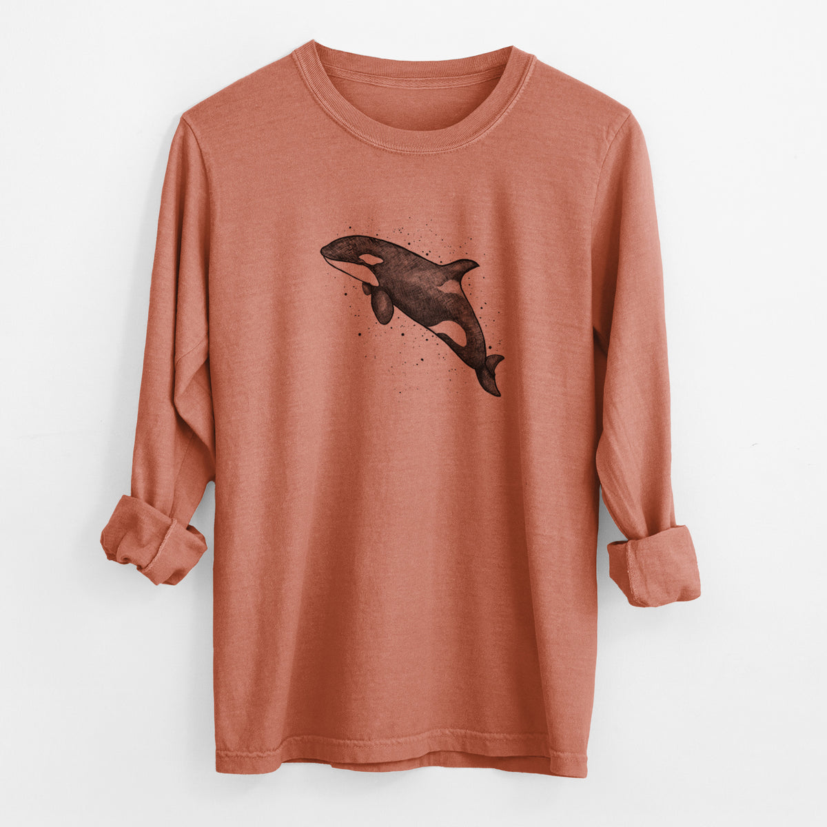 Yam burnt orange Comfort Colors long sleeve shirt laid flat with the cuffs rolled, printed with a black ink illustration of an orca leaping, with ink splatters.