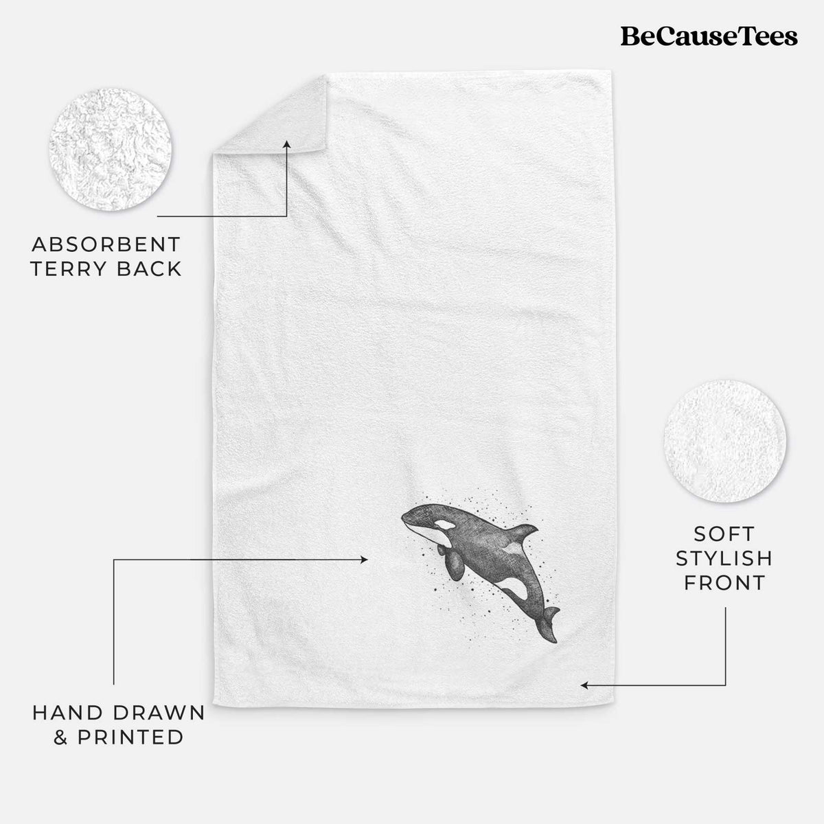 White hand towel printed with a black ink illustration of an orca leaping, with ink splatters.