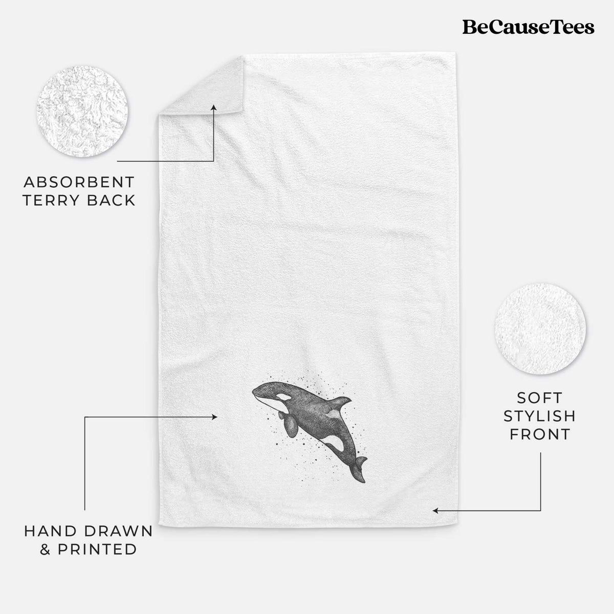 White hand towel printed with a black ink illustration of an orca leaping, with ink splatters.