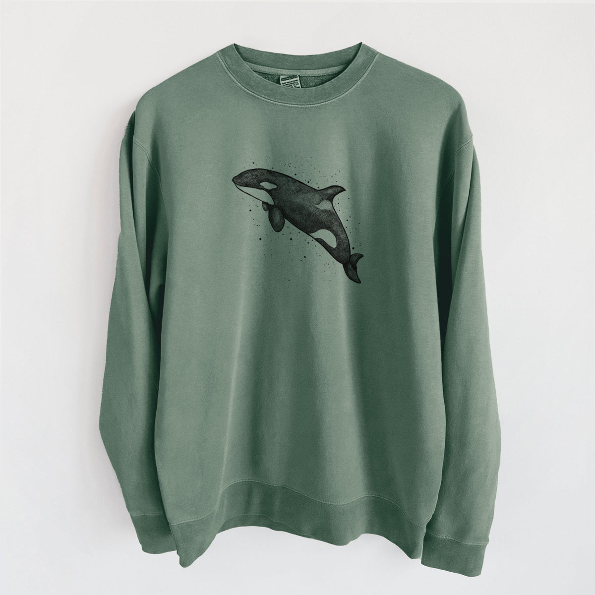 Alpine green pigment dyed crewneck sweatshirt laid flat, printed with a black ink illustration of an orca leaping, with ink splatters.