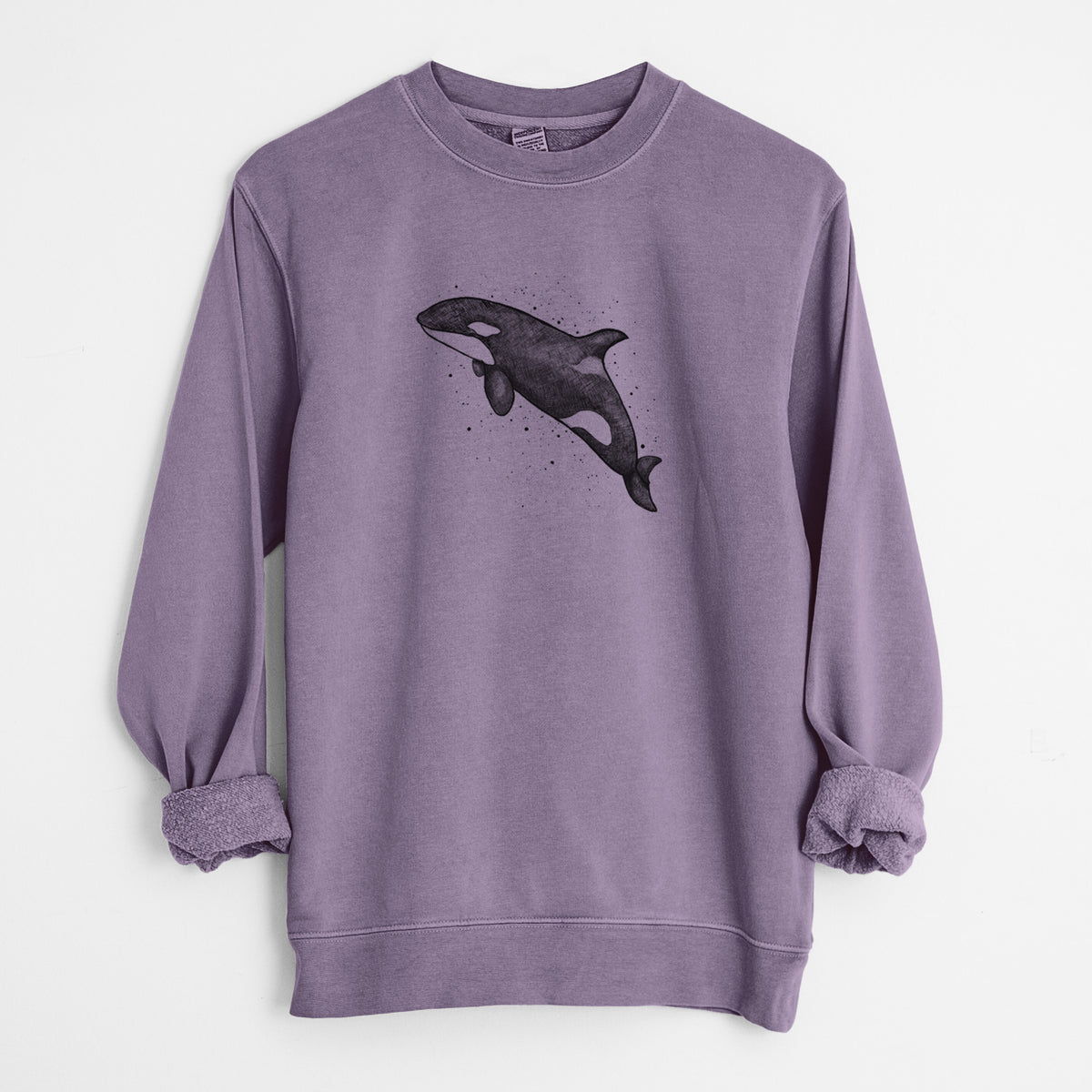 Plum purple pigment dyed crewneck sweatshirt laid flat with the sleeves rolled, printed with a black ink illustration of an orca leaping, with ink splatters.