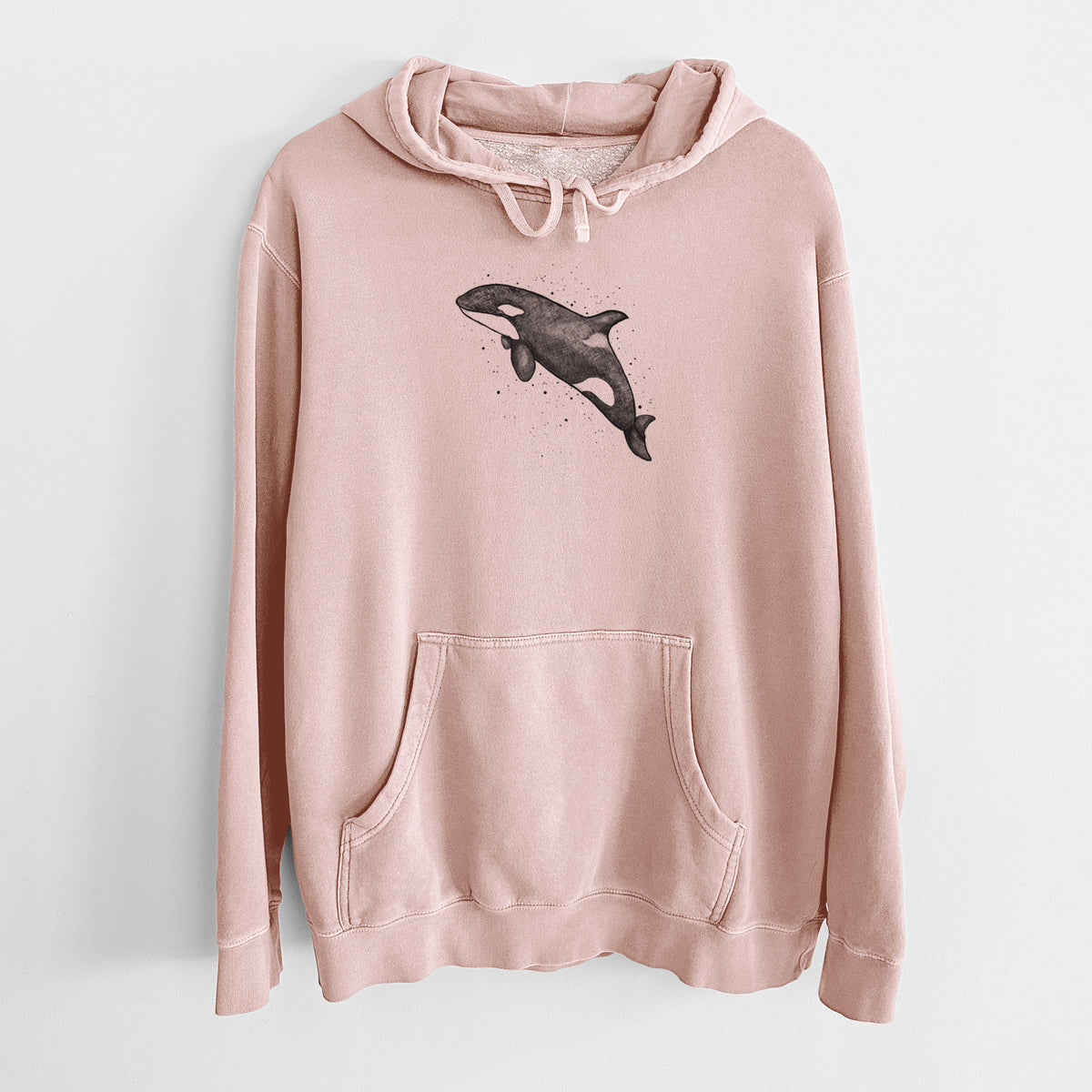 Dusty pink pigment dyed hoodie laid flat, printed with a black ink illustration of an orca leaping, with ink splatters.