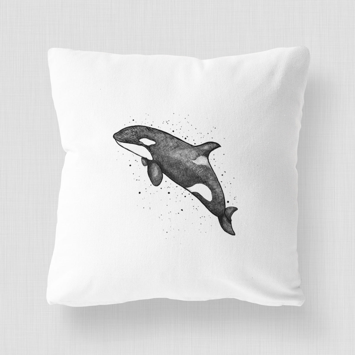 White pillow cover printed with a black ink illustration of an orca leaping, with ink splatters.