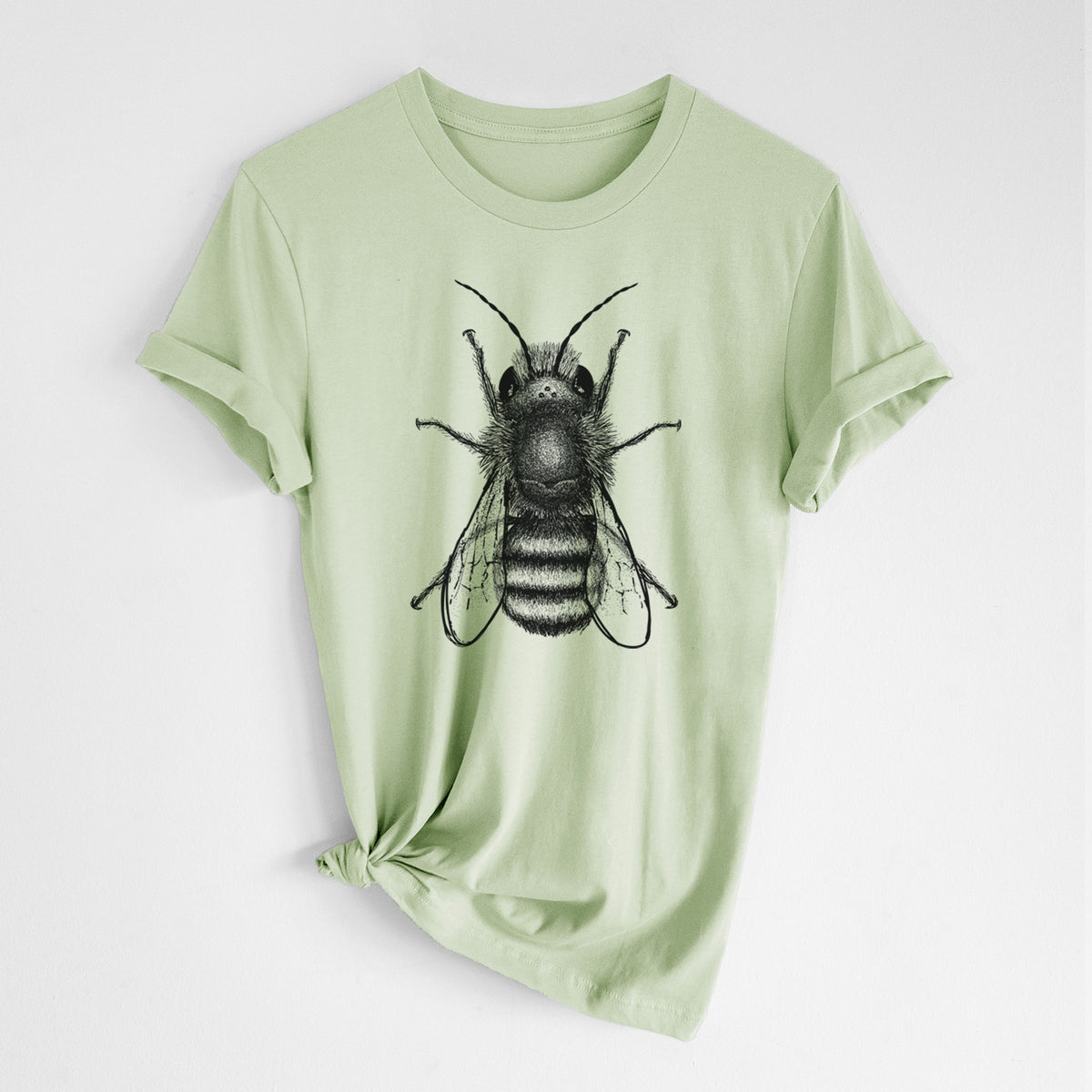 Spring green lightweight cotton t-shirt laid flat with the sleeves rolled, printed with a detailed black ink illustration of a red mason bee with its wings spread, seen from above.