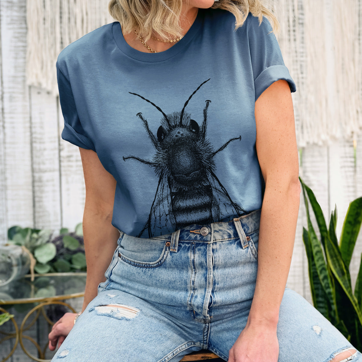 Woman wearing a steel blue lightweight cotton t-shirt printed with a detailed black ink illustration of a red mason bee with its wings spread, seen from above.