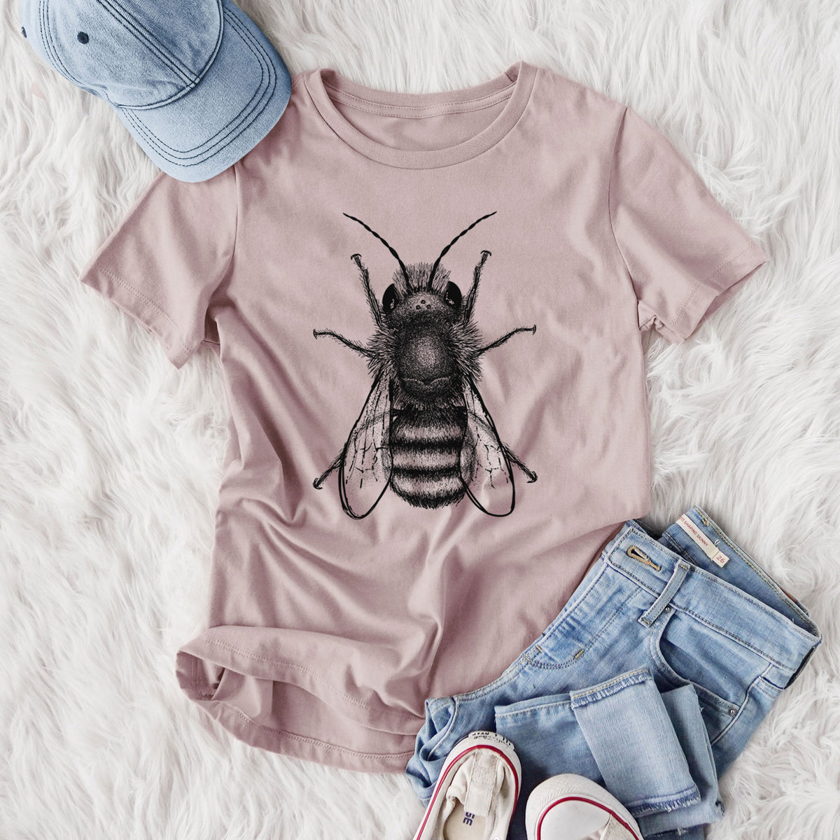 Women's relaxed fit cotton t-shirt printed with a detailed black ink illustration of a red mason bee with its wings spread, seen from above, styled flat on a white faux fur rug with jeans.