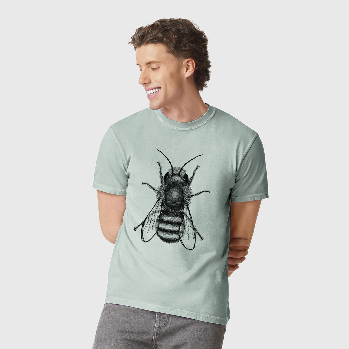 Man wearing a Comfort Colors t-shirt printed with a detailed black ink illustration of a red mason bee with its wings spread, seen from above.