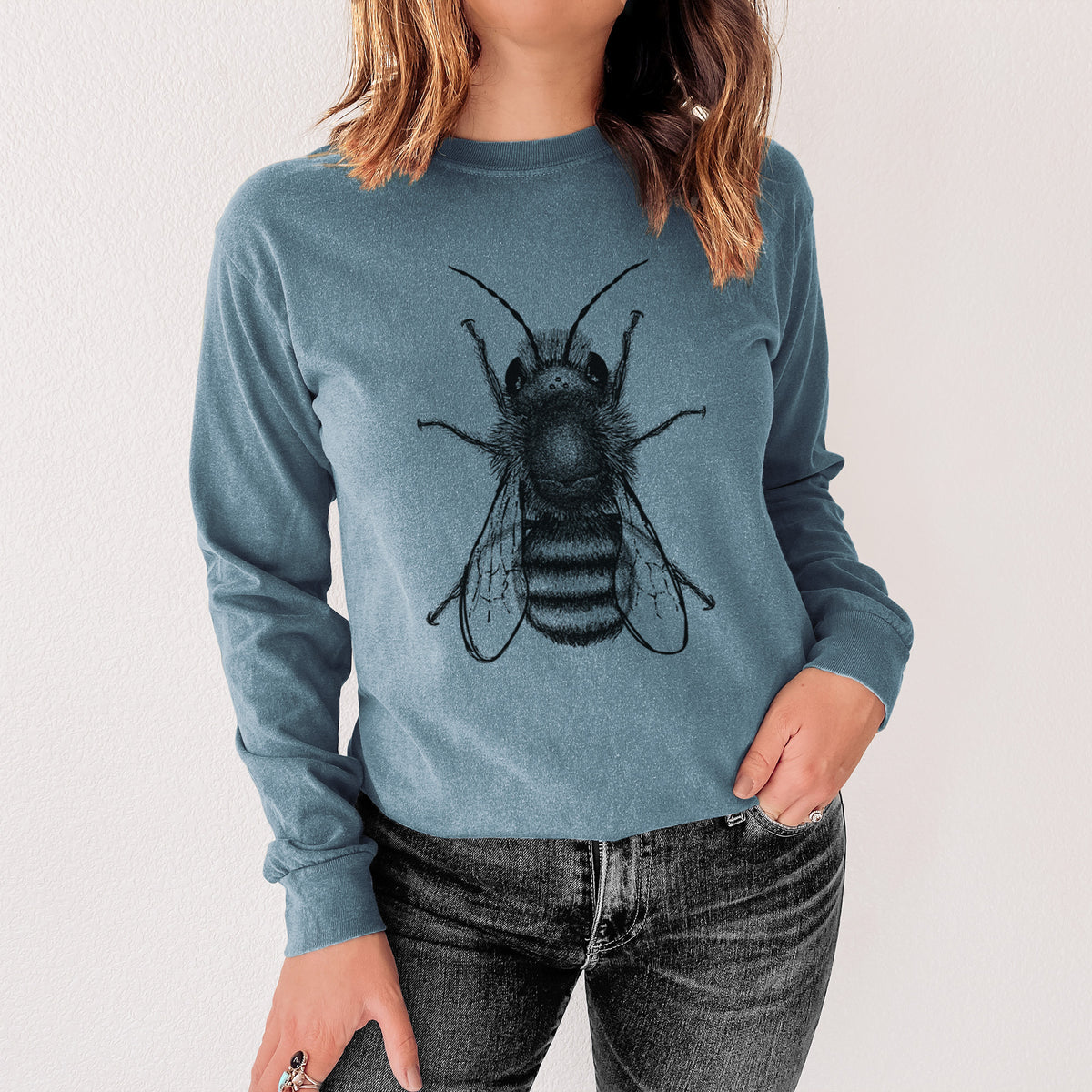 Steel blue Comfort Colors long sleeve shirt printed with a detailed black ink illustration of a red mason bee with its wings spread, seen from above, shown in a lifestyle photo.
