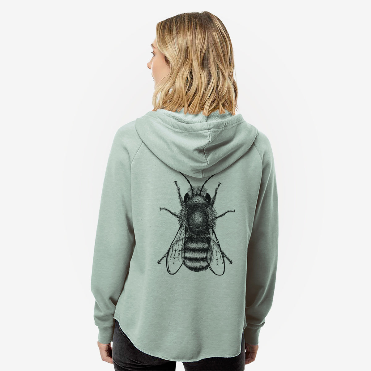 Woman wearing a sage green women's Cali Wave zip-up sweatshirt printed with a detailed black ink illustration of a red mason bee with its wings spread, seen from above, seen from behind.