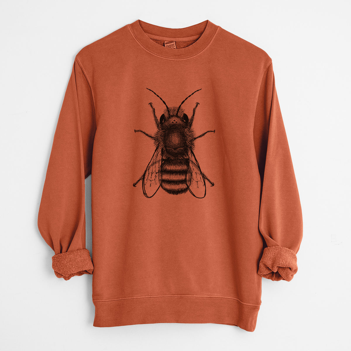 Amber orange pigment dyed crewneck sweatshirt laid flat with the sleeves rolled, printed with a detailed black ink illustration of a red mason bee with its wings spread, seen from above.