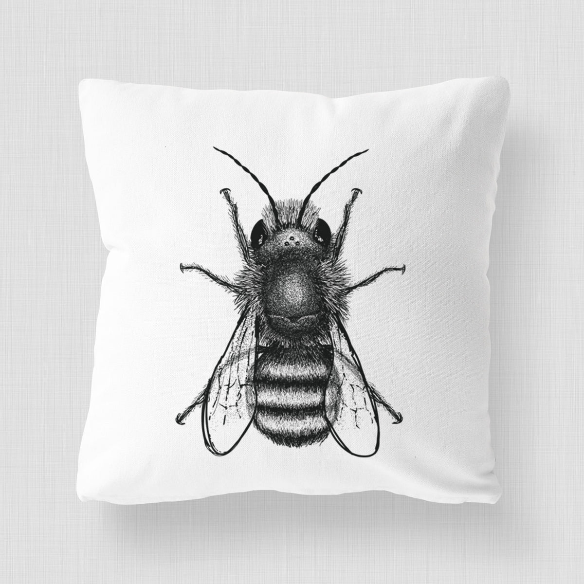 White pillow cover printed with a detailed black ink illustration of a red mason bee with its wings spread, seen from above.