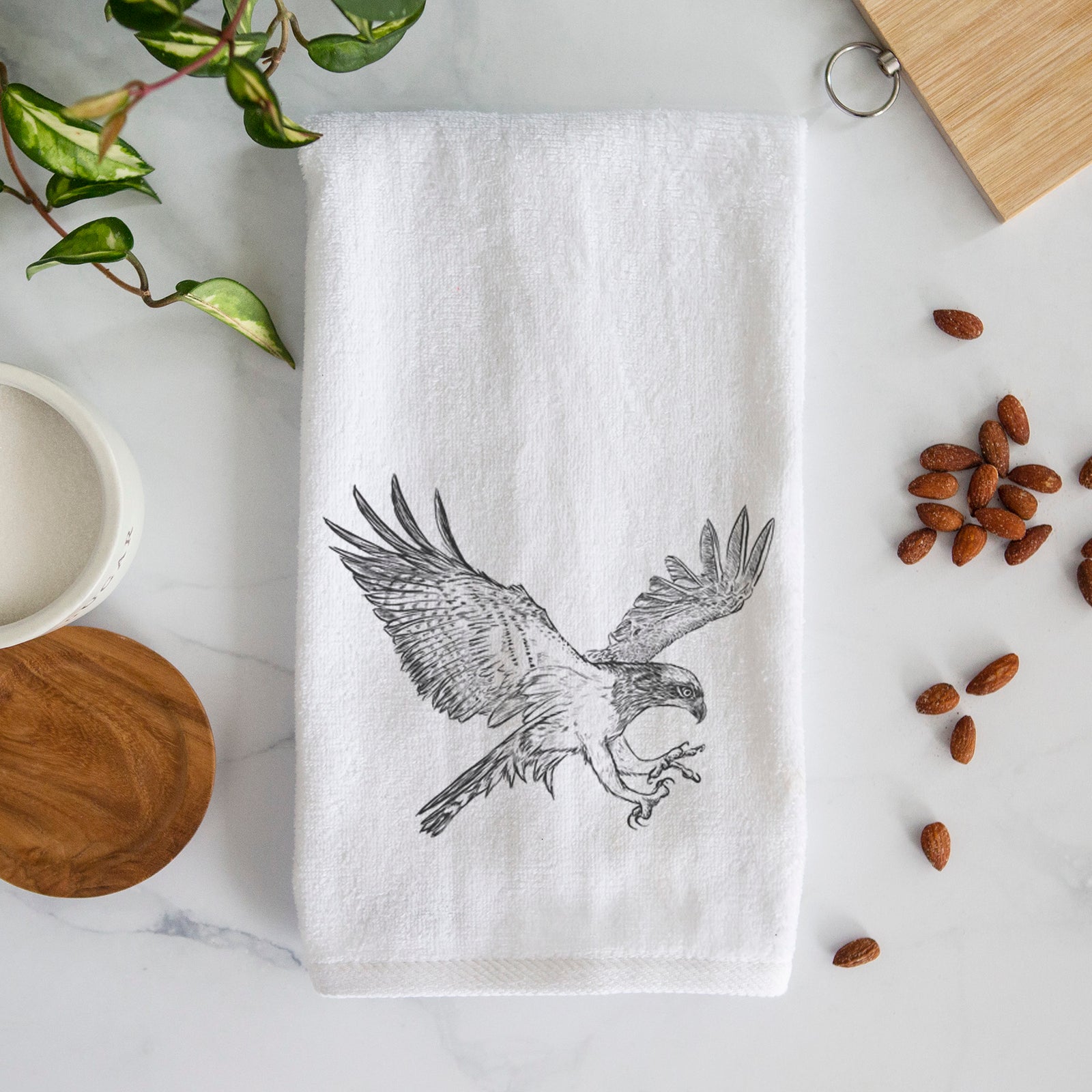 White hand towel printed with a black ink illustration of an osprey in flight with its wings spread.