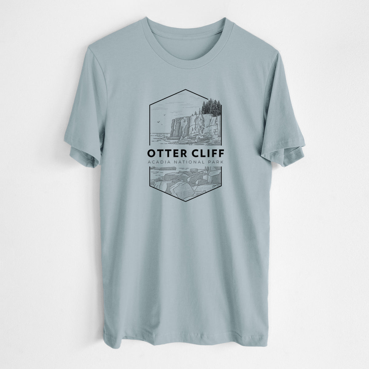 Vintage denim lightweight cotton t-shirt laid flat, printed with a black line art badge of Otter Cliff above the ocean, with the words Otter Cliff, Acadia National Park.