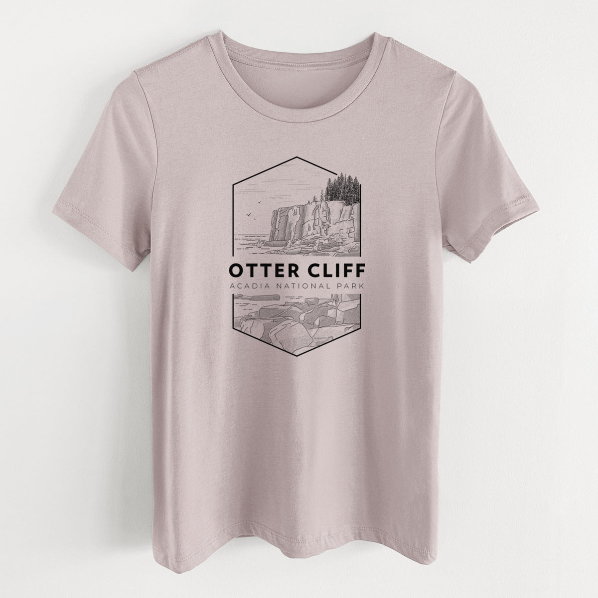 Pink gravel women's relaxed fit cotton t-shirt laid flat, printed with a black line art badge of Otter Cliff above the ocean, with the words Otter Cliff, Acadia National Park.