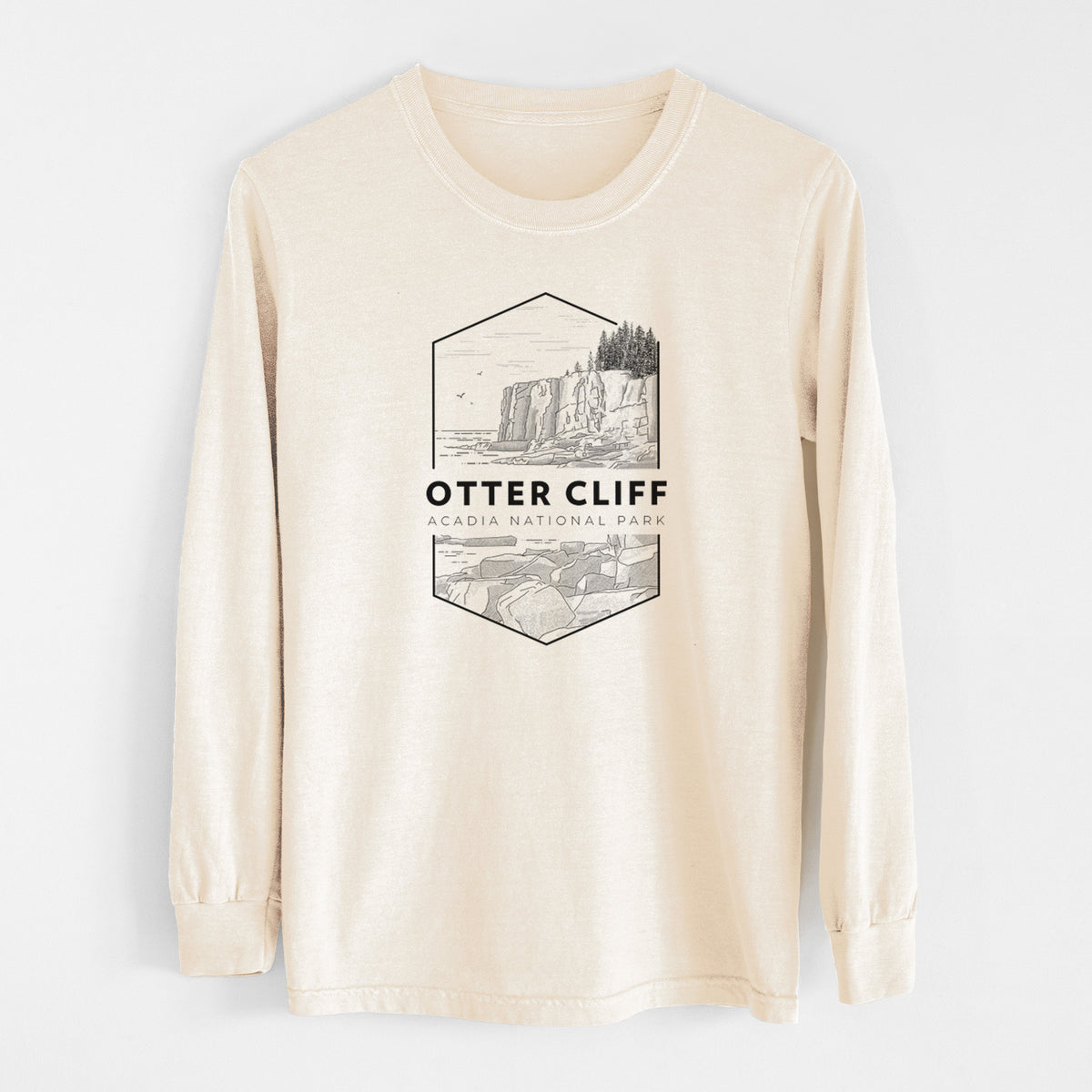 Ivory Comfort Colors long sleeve shirt laid flat, printed with a black line art badge of Otter Cliff above the ocean, with the words Otter Cliff, Acadia National Park.
