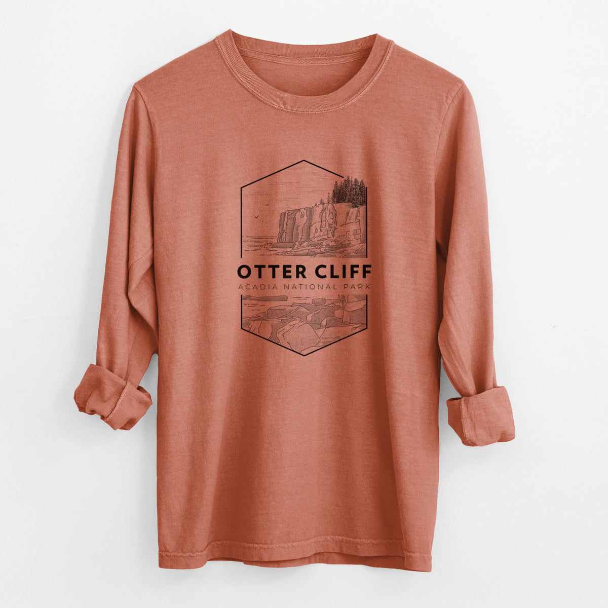 Yam burnt orange Comfort Colors long sleeve shirt laid flat with the cuffs rolled, printed with a black line art badge of Otter Cliff above the ocean, with the words Otter Cliff, Acadia National Park.