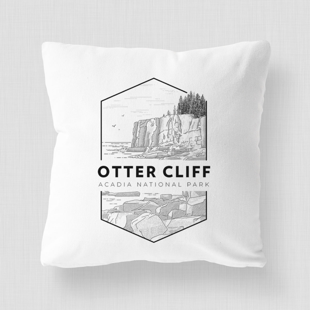 White pillow cover printed with a black line art badge of Otter Cliff above the ocean, with the words Otter Cliff, Acadia National Park.