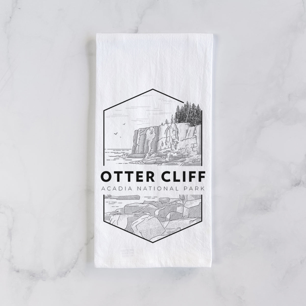 White cotton tea towel laid flat on marble, printed with a black line art badge of Otter Cliff above the ocean, with the words Otter Cliff, Acadia National Park.