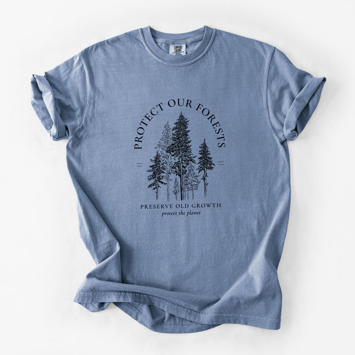 Blue jean Comfort Colors t-shirt laid flat, printed with a black ink illustration of a stand of tall pine trees, framed by the words Protect Our Forests, Preserve Old Growth.